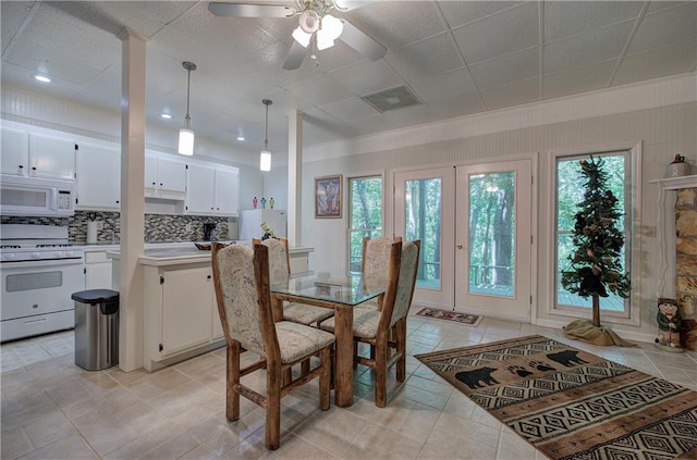 tiled dining space with ceiling fan and wooden walls