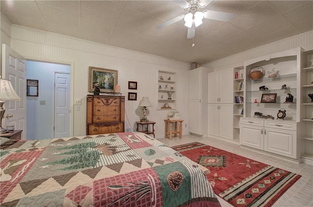 bedroom featuring ceiling fan and wooden walls