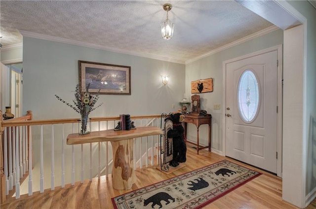 foyer entrance with crown molding, a textured ceiling, and light wood-type flooring