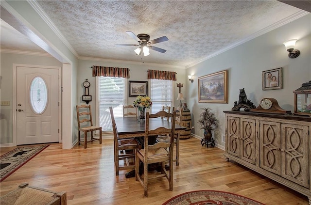 dining room featuring a textured ceiling, light wood-type flooring, ceiling fan, and crown molding