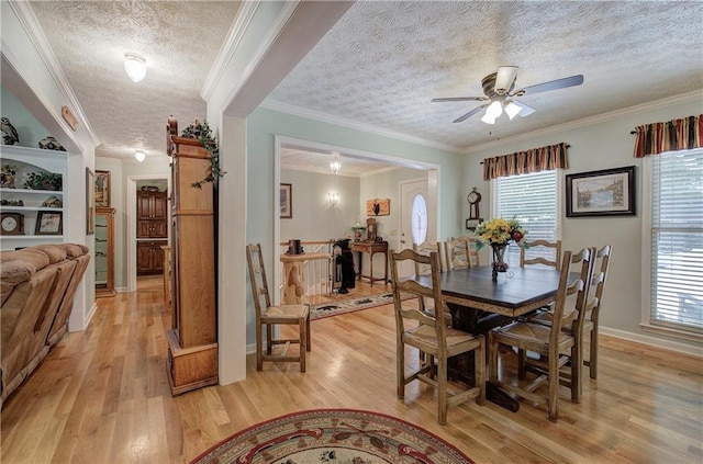 dining area featuring a healthy amount of sunlight, light wood-type flooring, and ornamental molding