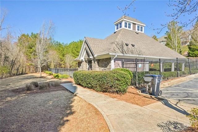 2726 Pierce Brennen Ct, Lawrenceville, GA 30043 - view of home's exterior with stone siding, a shingled roof, and fence