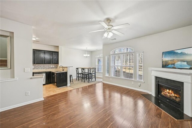 2726 Pierce Brennen Ct, Lawrenceville, GA 30043 - unfurnished living room with wood finished floors, visible vents, a sink, a glass covered fireplace, and ceiling fan with notable chandelier