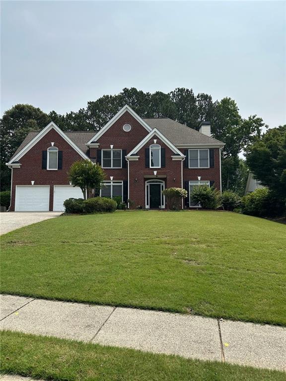 3381 Walkers Ridge Rd, Dacula, GA 30019 - traditional-style home with a garage, a front lawn, concrete driveway, and brick siding
