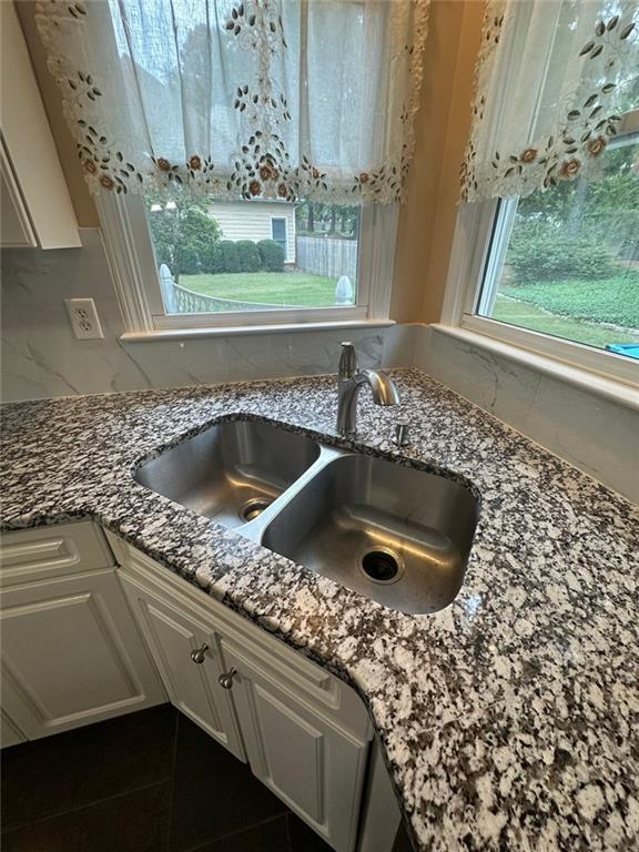 3381 Walkers Ridge Rd, Dacula, GA 30019 - kitchen view of a sink, dark stone counters, decorative backsplash, and white cabinetry