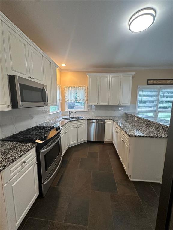 3381 Walkers Ridge Rd, Dacula, GA 30019 - kitchen featuring stainless steel appliances, white cabinets, light stone counters, ornamental molding, and a peninsula