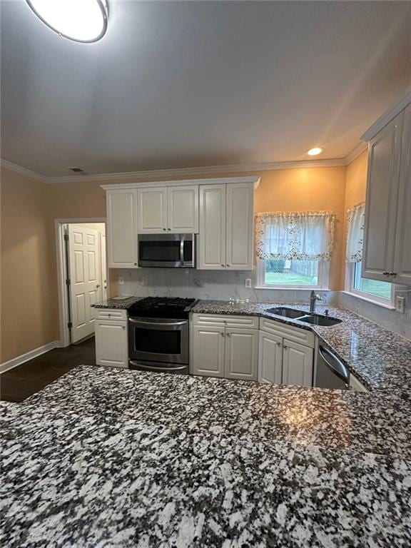 3381 Walkers Ridge Rd, Dacula, GA 30019 - kitchen with appliances with stainless steel finishes, crown molding, white cabinets, dark stone counters, and a sink
