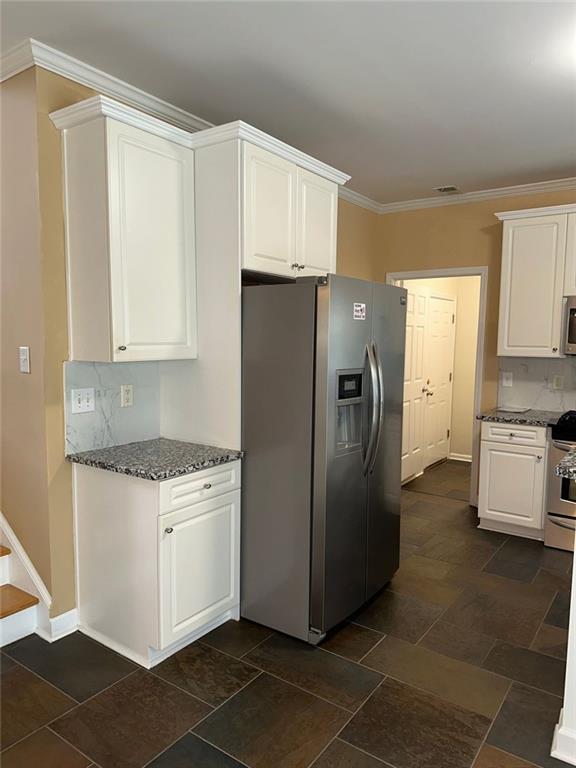 3381 Walkers Ridge Rd, Dacula, GA 30019 - kitchen featuring stainless steel appliances, white cabinets, dark stone counters, crown molding, and decorative backsplash