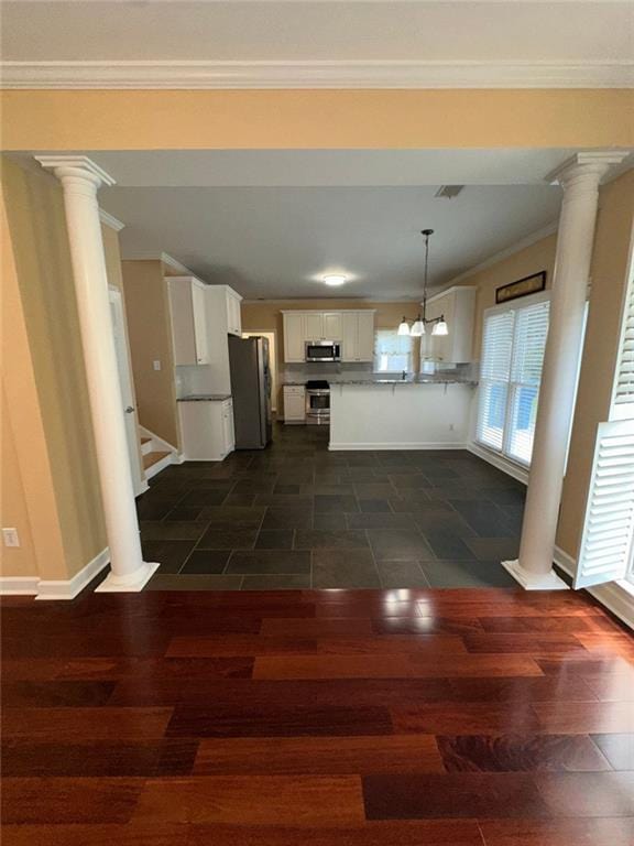 3381 Walkers Ridge Rd, Dacula, GA 30019 - kitchen featuring appliances with stainless steel finishes, decorative columns, white cabinetry, baseboards, and crown molding
