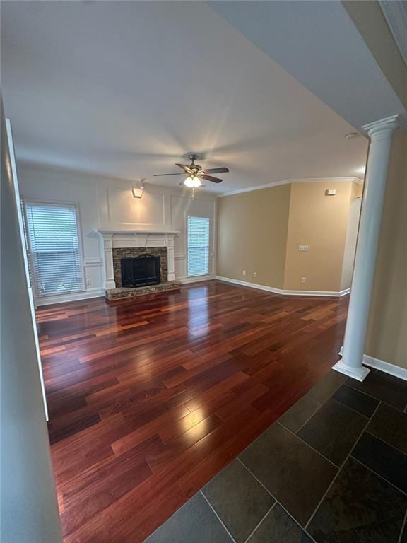 3381 Walkers Ridge Rd, Dacula, GA 30019 - unfurnished living room featuring ornate columns, ceiling fan, a stone fireplace, wood finished floors, and baseboards