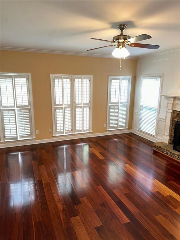 3381 Walkers Ridge Rd, Dacula, GA 30019 - unfurnished living room with ceiling fan, a fireplace with raised hearth, dark wood-style flooring, ornamental molding, and baseboards