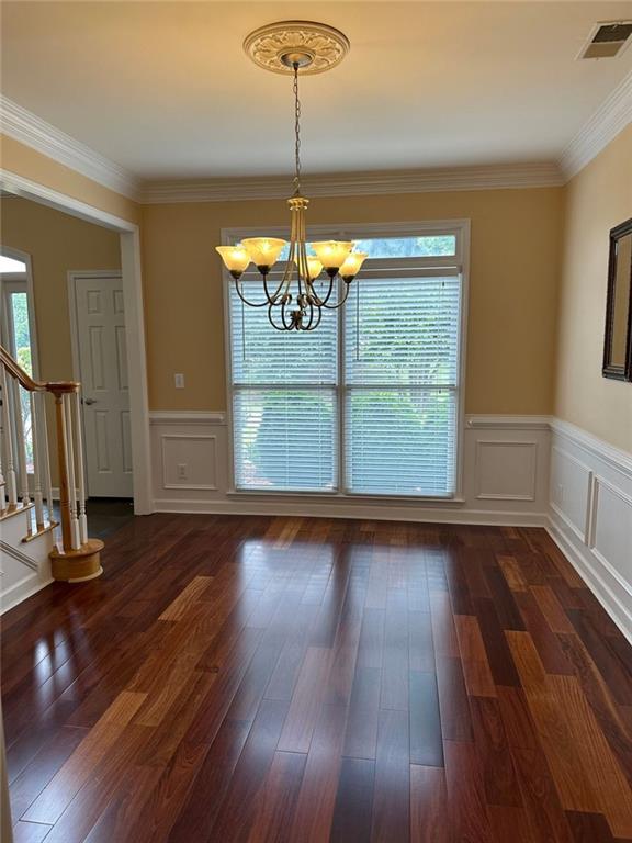 3381 Walkers Ridge Rd, Dacula, GA 30019 - unfurnished dining area featuring a chandelier, stairs, a wainscoted wall, dark wood-type flooring, and ornamental molding