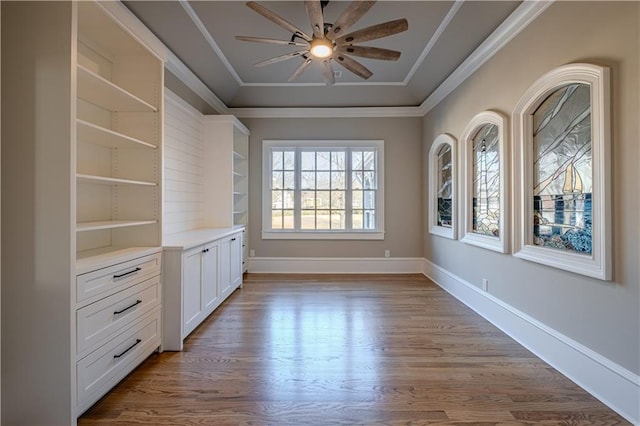 interior space with baseboards, ornamental molding, ceiling fan, and wood finished floors