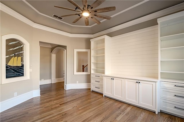 spare room featuring ceiling fan, light wood finished floors, arched walkways, visible vents, and ornamental molding