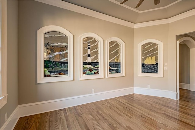 spare room featuring a ceiling fan, baseboards, ornamental molding, and wood finished floors