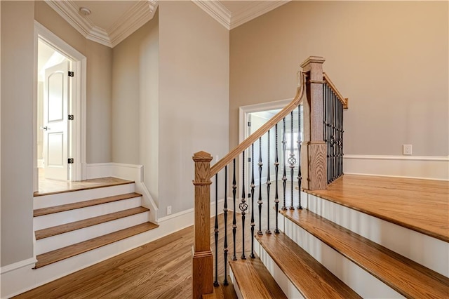 stairway with ornamental molding and wood finished floors