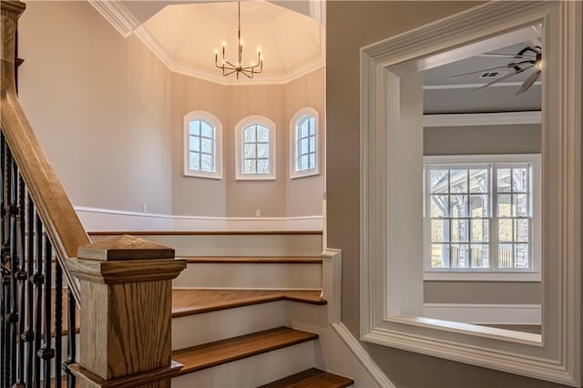 staircase featuring ornamental molding, a healthy amount of sunlight, and ceiling fan with notable chandelier