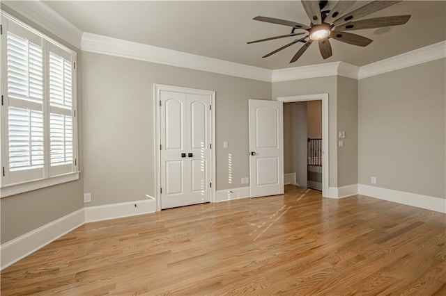 unfurnished bedroom with crown molding, baseboards, and light wood-style flooring
