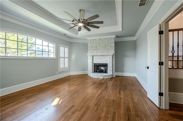 unfurnished living room with ceiling fan, visible vents, crown molding, wood finished floors, and a raised ceiling