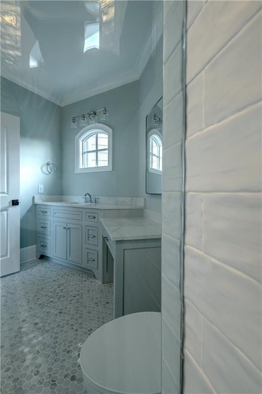 bathroom featuring crown molding, baseboards, and vanity