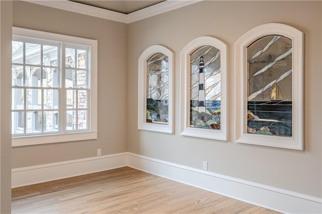 spare room featuring plenty of natural light, crown molding, and wood finished floors