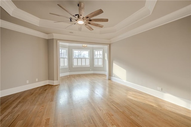 unfurnished room with crown molding, light wood finished floors, ceiling fan, and a tray ceiling