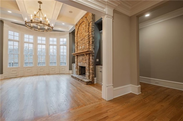 unfurnished living room featuring crown molding, baseboards, a stone fireplace, a chandelier, and coffered ceiling