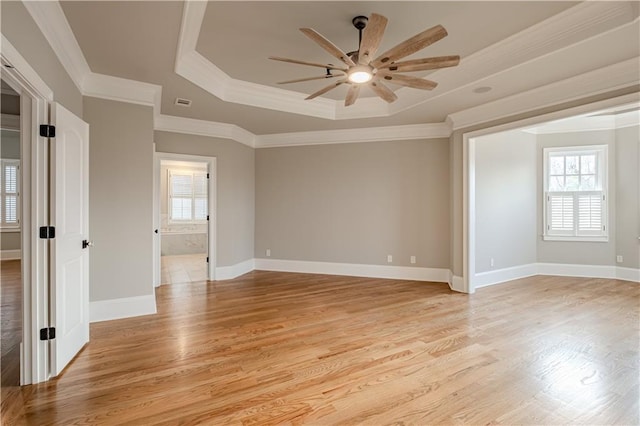 unfurnished room with crown molding, light wood-style flooring, ceiling fan, and a tray ceiling