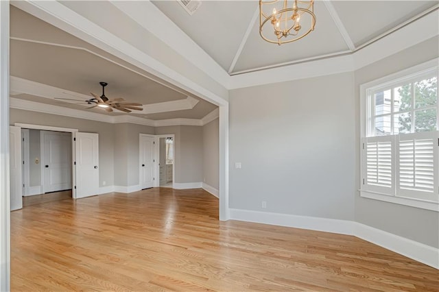 spare room featuring ceiling fan with notable chandelier, light wood-style floors, vaulted ceiling, and visible vents