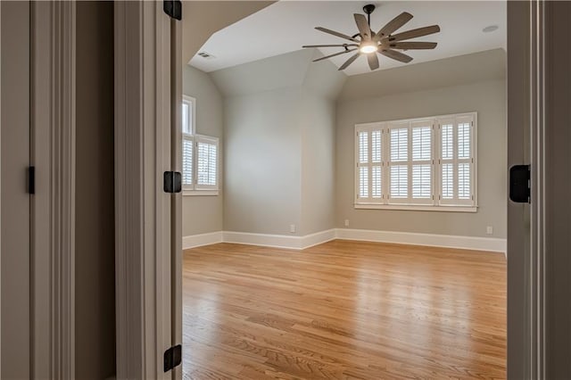 spare room featuring baseboards, a ceiling fan, light wood finished floors, and vaulted ceiling