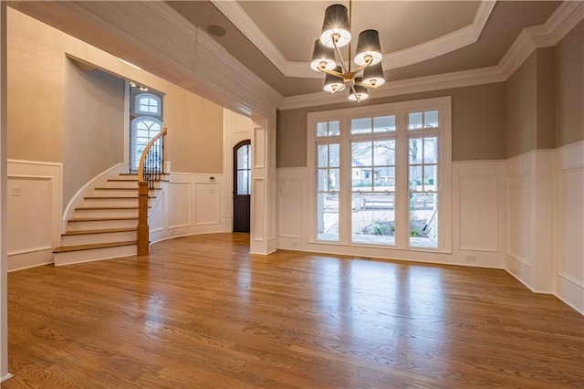 interior space with a notable chandelier, a wainscoted wall, stairway, and a decorative wall