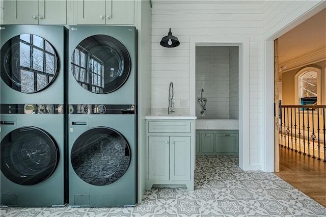 laundry room featuring a sink, cabinet space, and stacked washer / dryer