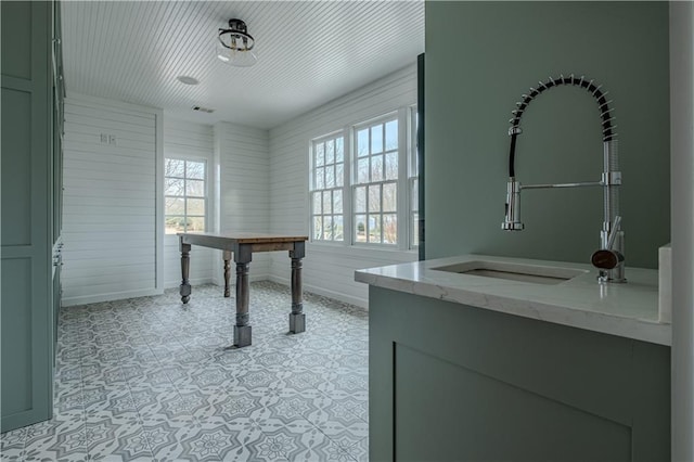 unfurnished office featuring baseboards, a sink, and wood walls