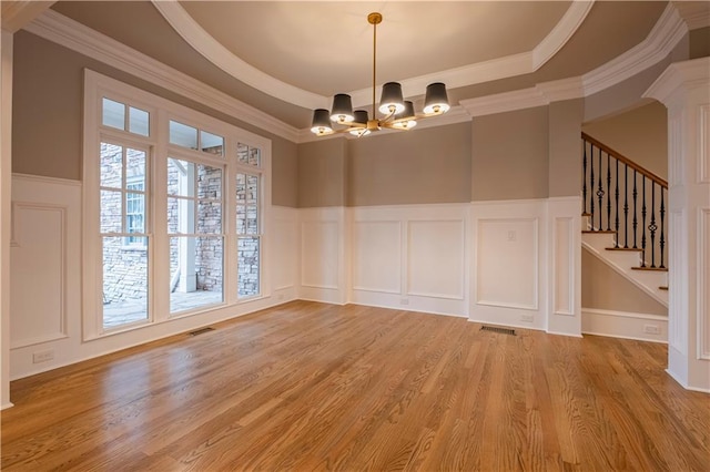 unfurnished dining area with a notable chandelier, a decorative wall, light wood finished floors, and visible vents