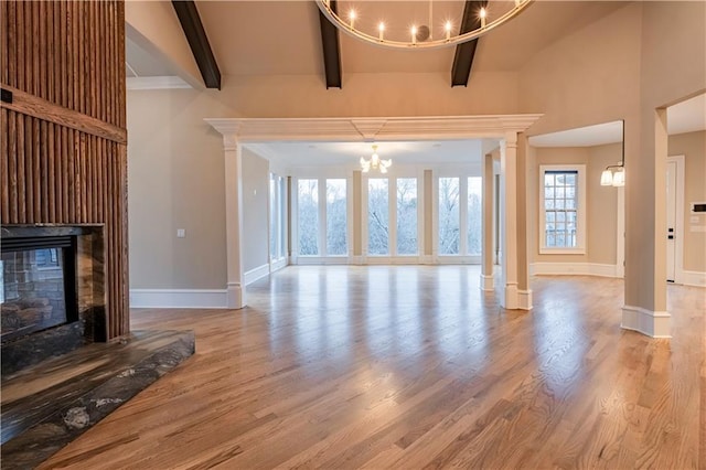 unfurnished living room featuring a multi sided fireplace, beam ceiling, wood finished floors, and a chandelier