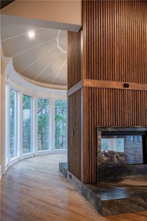 interior space featuring a multi sided fireplace, ornamental molding, and wood finished floors