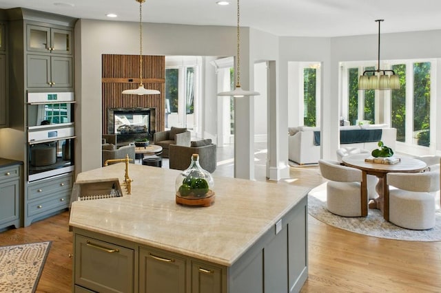 6756 Hedge Row Ln, Gainesville, GA 30506 - kitchen featuring stainless steel double oven, open floor plan, a center island with sink, light wood-type flooring, and recessed lighting