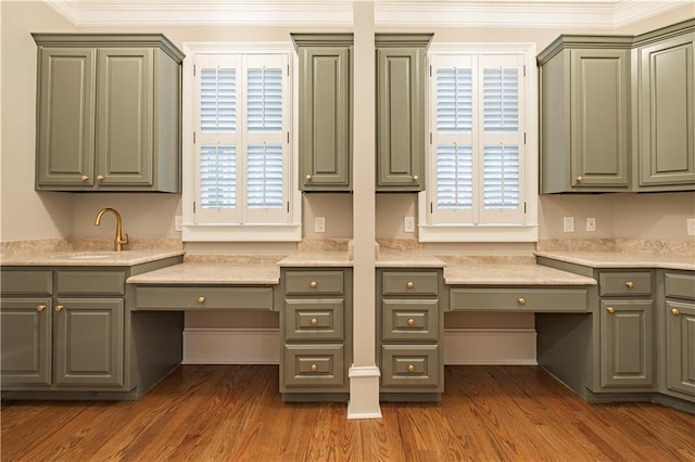 unfurnished office featuring built in study area, a sink, wood finished floors, and ornamental molding