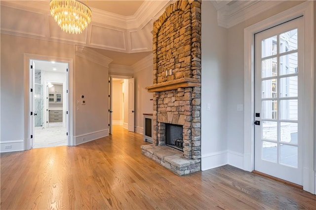unfurnished living room with a notable chandelier, ornamental molding, wood finished floors, and a fireplace