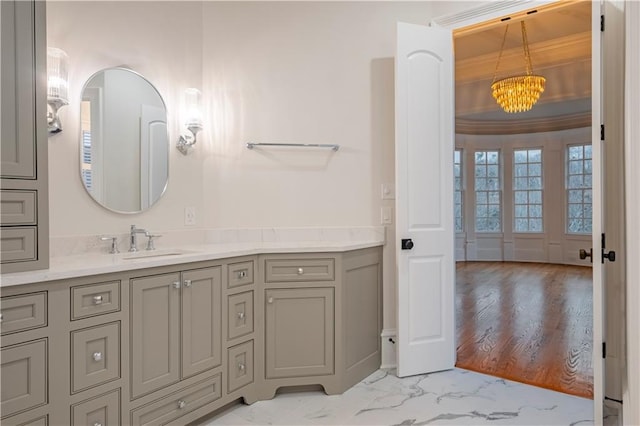 bathroom featuring an inviting chandelier, ornamental molding, marble finish floor, and vanity