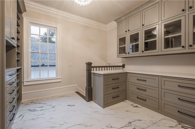 kitchen featuring gray cabinetry, ornamental molding, and marble finish floor