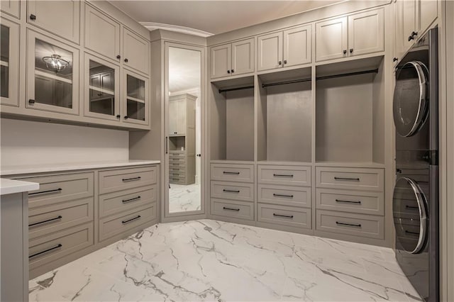 spacious closet featuring stacked washer / dryer and marble finish floor
