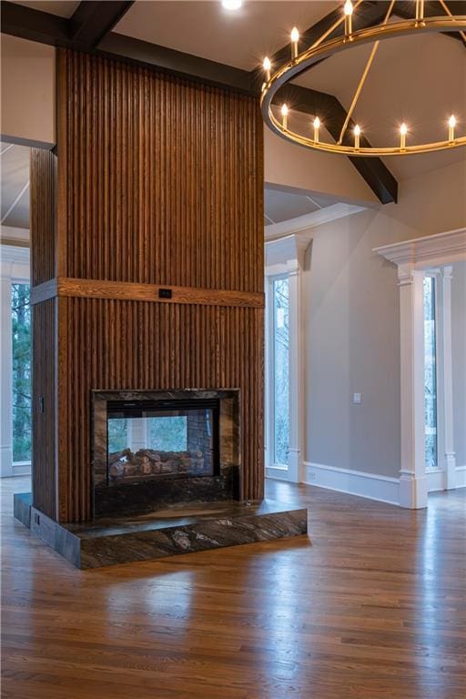 details with a multi sided fireplace, baseboards, ornamental molding, and wood finished floors