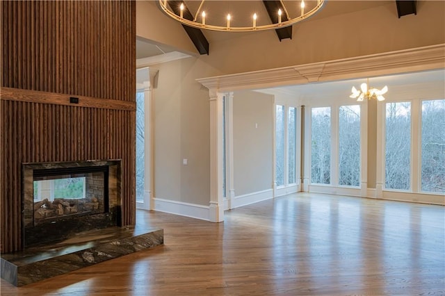 unfurnished living room with an inviting chandelier, ornamental molding, wood finished floors, baseboards, and a multi sided fireplace