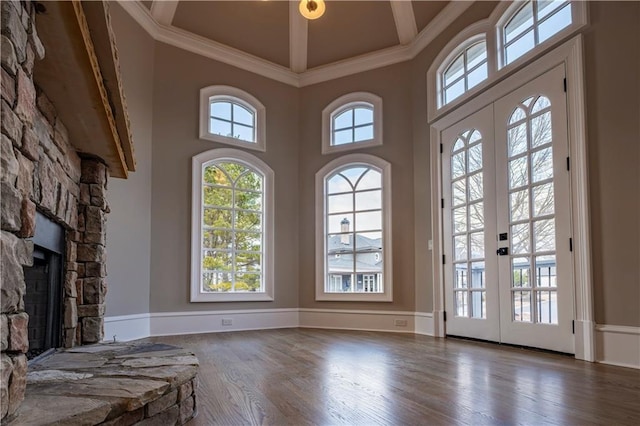 unfurnished living room with crown molding, a high ceiling, a fireplace, french doors, and wood finished floors