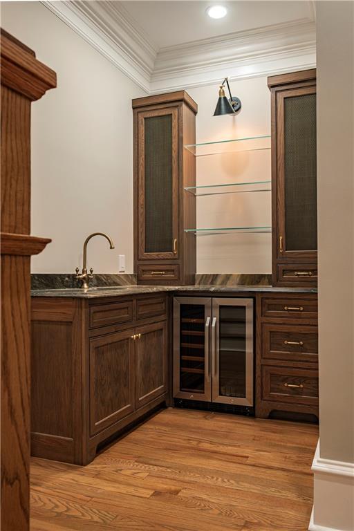 bar with crown molding, indoor bar, light wood-style floors, and wine cooler