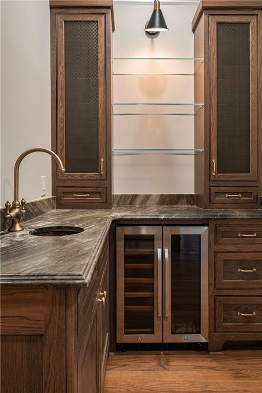 bar with a sink, indoor wet bar, beverage cooler, and wood finished floors