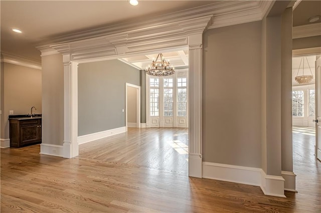 unfurnished dining area with a healthy amount of sunlight, ornamental molding, ornate columns, and a notable chandelier