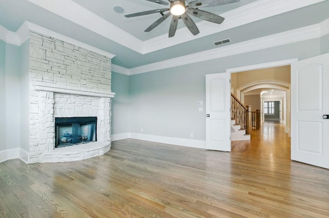 6756 Hedge Row Ln, Gainesville, GA 30506 - unfurnished living room with a stone fireplace, a ceiling fan, arched walkways, stairs, and light wood finished floors