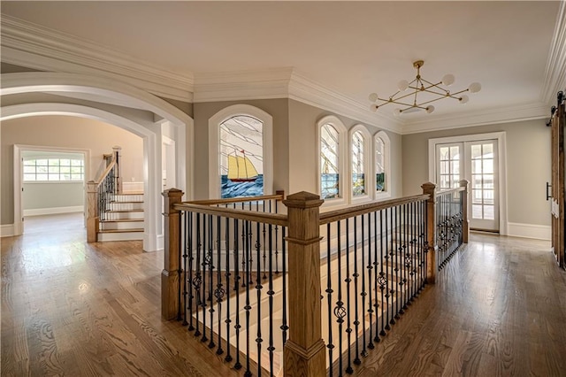 hallway with baseboards, crown molding, wood finished floors, and a chandelier